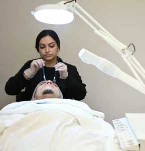 Esthetician student works on hydrating facial with a male client